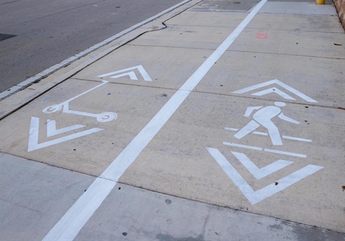 Sidewalk showing striped scooter and pedestrian lanes.