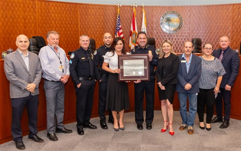 Chief Santiago holding accreditation plaque with Commissioners at meeting